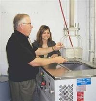 MicroCare Sr. VP Jay Tourigny and Chemist Venesia Hurtubise operate a medium-sized Branson vapor degreaser equipped with an automated hoist