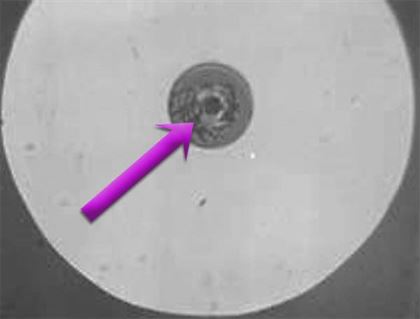 This image shows damage on a fiber end-face from contamination which was not removed before the connector was irradiated with a 100mW laser. The contamination absorbed the light, converted it into heat, and fused the central contact area of the fiber. Image courtesy NTT AT of Japan.