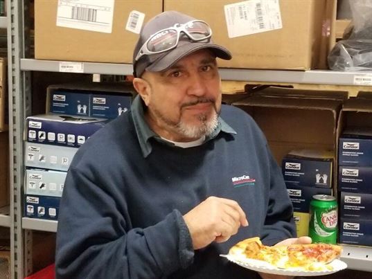 Juan enjoys a quick bite at the 35th anniversary pizza party.